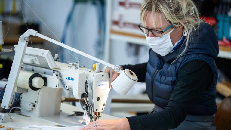 Die Mitarbeiterin einer Firma in Mecklenburg-Vorpommern näht Mundschutzmasken zum Schutz vor Coronaviren. Das Unternehmen stellt normalerweise Kleidung für Restaurantküchen her und hat erst vor wenigen Tagen die Produktion auf Schutzmasken umgestellt.