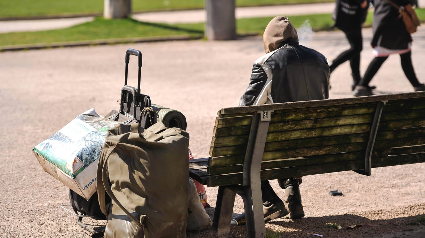 Ein Obdachloser sitzt auf einer Parkbank (Symboldbild): In Mainz können 30 wohnungslose Menschen in ein Hotel ziehen.
