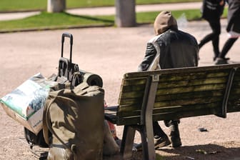 Ein Obdachloser sitzt auf einer Parkbank (Symboldbild): In Mainz können 30 wohnungslose Menschen in ein Hotel ziehen.