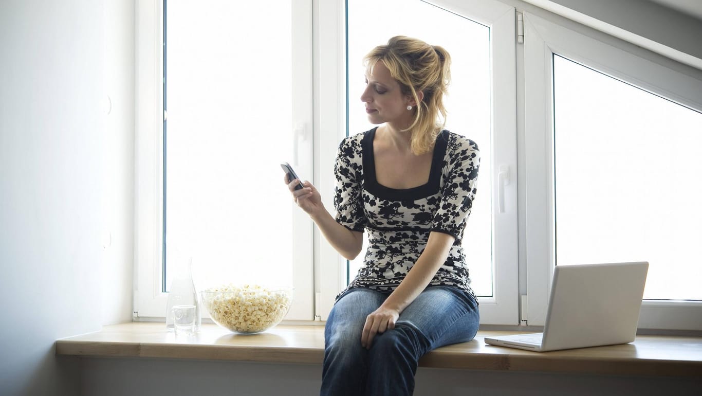 Junge Frau mit Smartphone in der Hand: Bei diesen Telefonnummern sollte man nicht rangehen