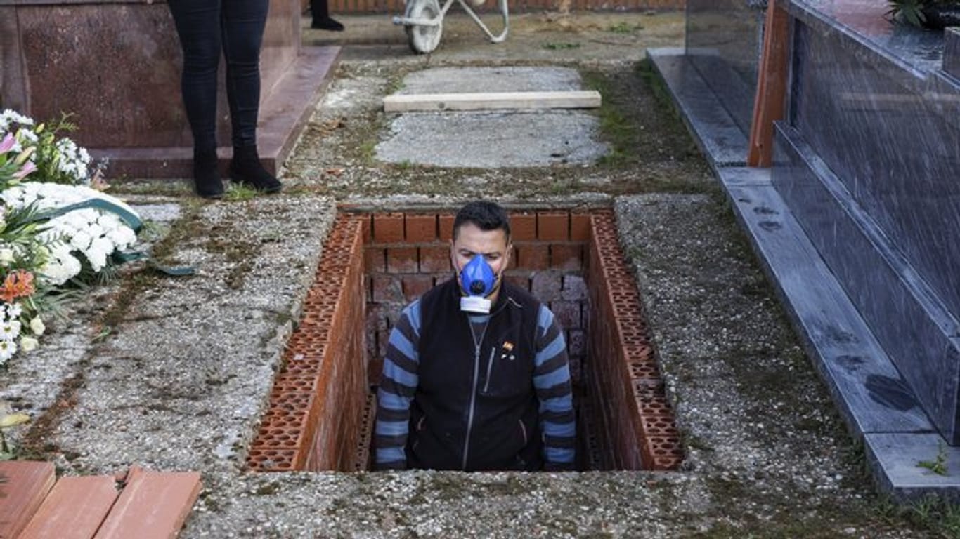 Ein Leichenbestatter in Spanien bereitet ein Grab vor während der Beerdigung einer 86-jährigen Frau mitten in der Corona-Krise.