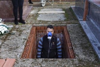 Ein Leichenbestatter in Spanien bereitet ein Grab vor während der Beerdigung einer 86-jährigen Frau mitten in der Corona-Krise.