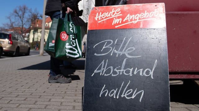 Ein Schild mit der Aufschrift "Bitte Abstand halten" auf einem Wochenmarkt. Ein Schild mit der Aufschrift "Bitte Abstand halten" auf einem Wochenmarkt.