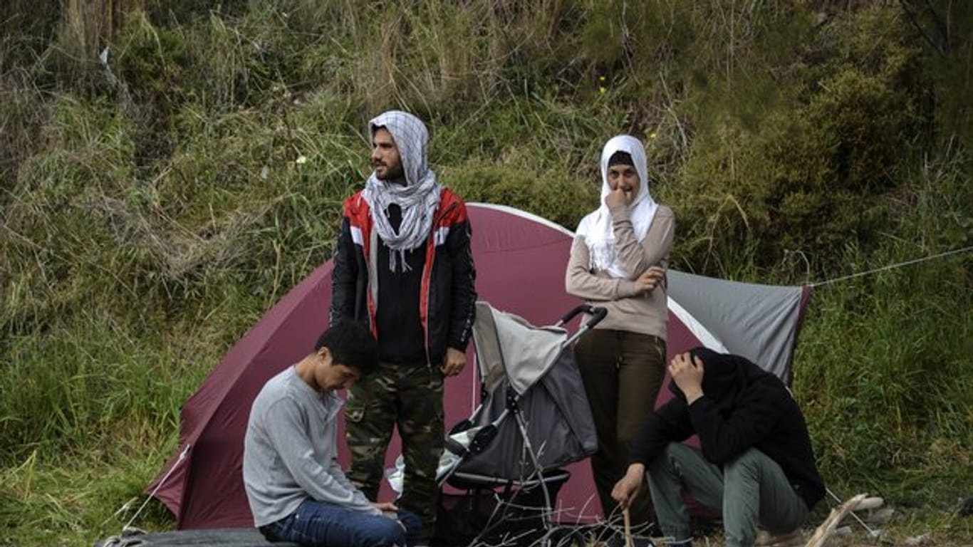 Migranten ruhen vor einem Zelt im Dorf Petra auf der nordöstlichen Ägäisinsel Lesbos in Griechenland.