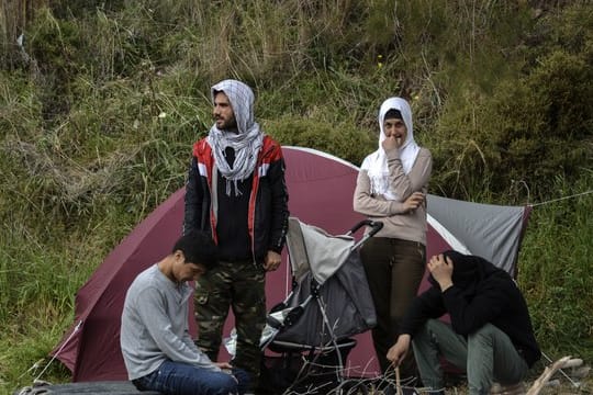Migranten ruhen vor einem Zelt im Dorf Petra auf der nordöstlichen Ägäisinsel Lesbos in Griechenland.