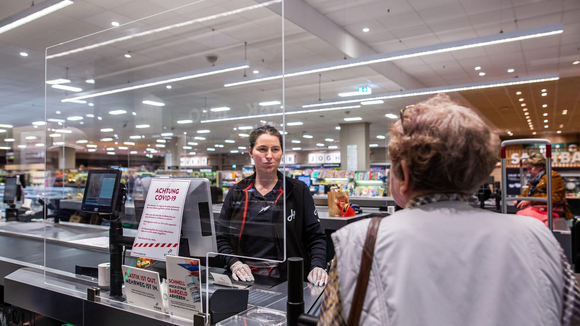 In Baden-Württemberg spricht eine Kundin im Kassenbereich eines Supermarktes mit einer Kassiererin: Der Einzelhandel ist durch die Coronavirus-Pandemie derzeit stark gefordert.