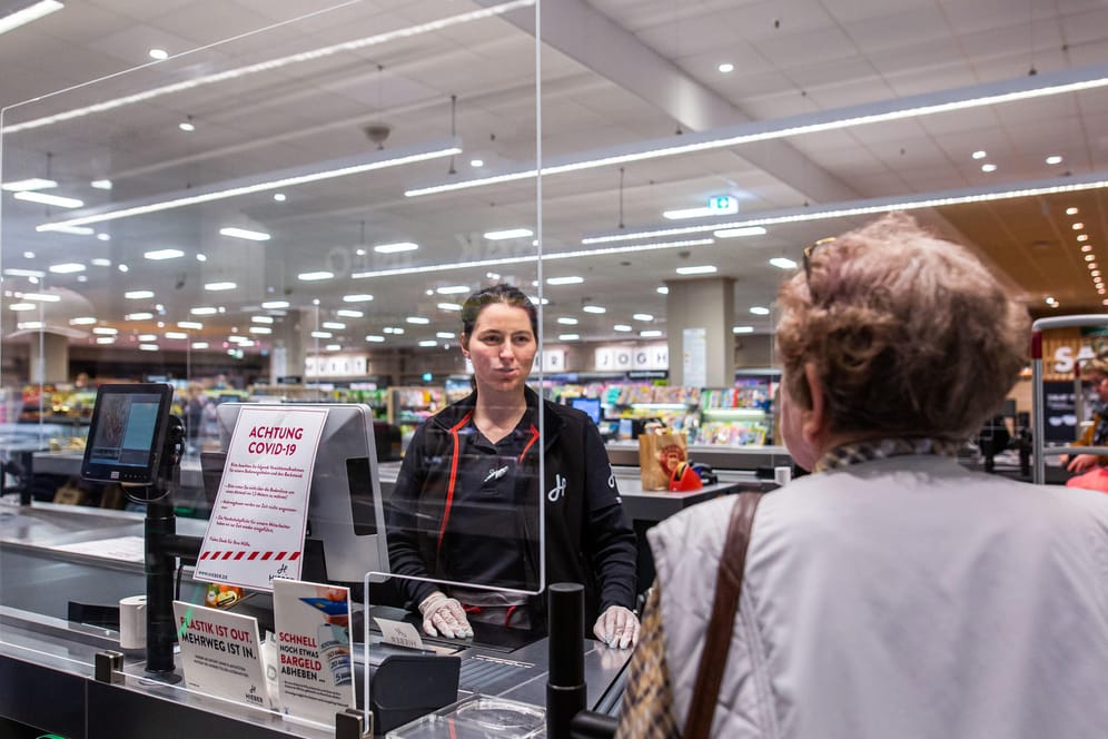 In Baden-Württemberg spricht eine Kundin im Kassenbereich eines Supermarktes mit einer Kassiererin: Der Einzelhandel ist durch die Coronavirus-Pandemie derzeit stark gefordert.