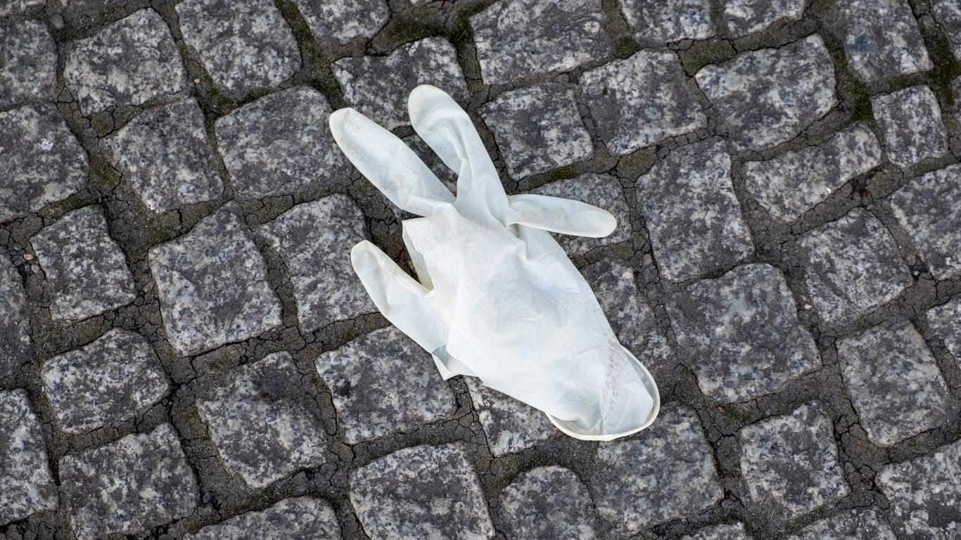 Ein Schutzhandschuh liegt auf einer Straße (Symbolbild): Viele Düsseldorfer ärgern sich über achtlos weggeworfene Corona-Hygieneartikel.