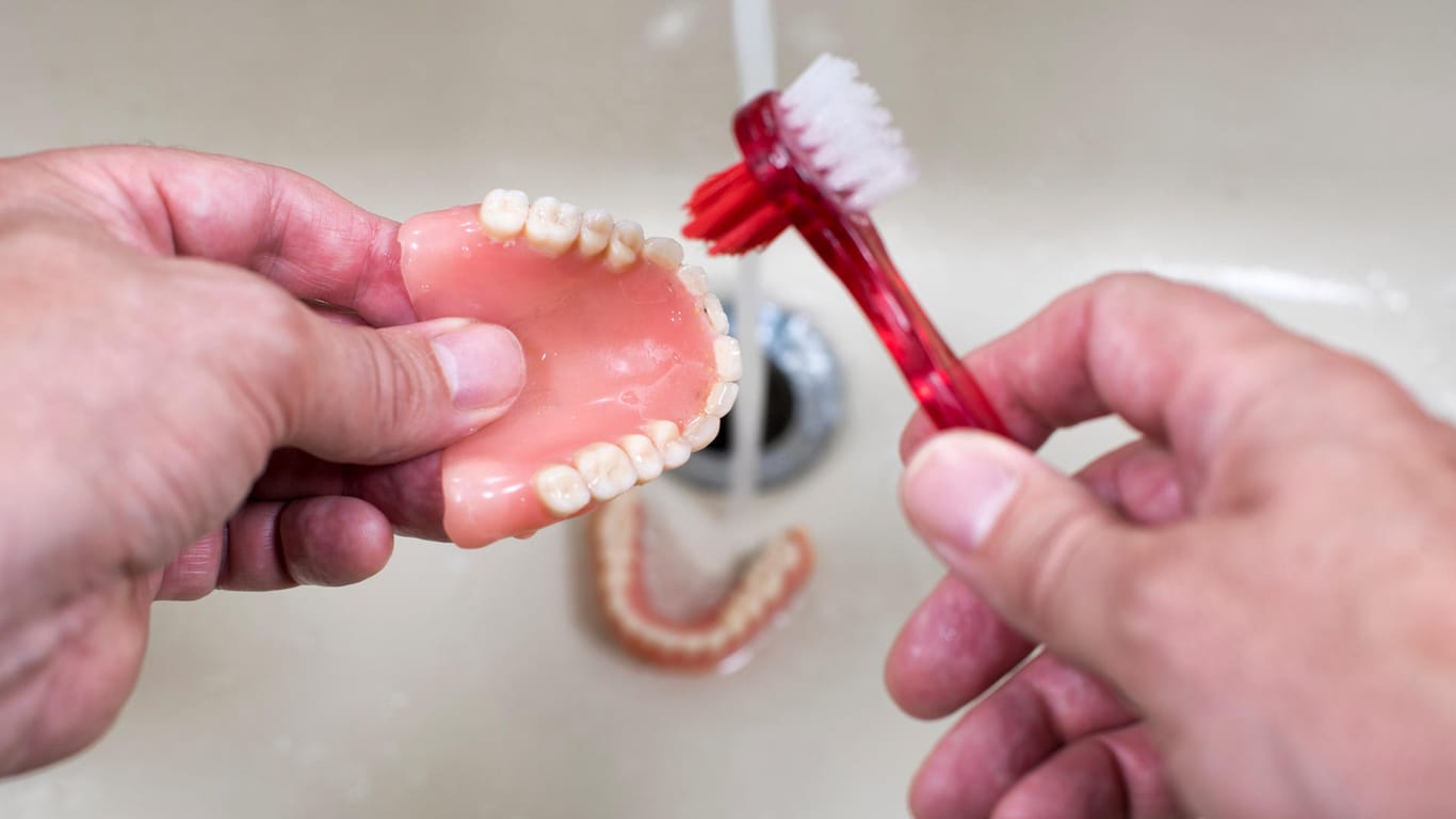 Zahnpflege: Eine spezielle Prothesenbürste kann dabei helfen, den Zahnersatz gründlicher zu reinigen.