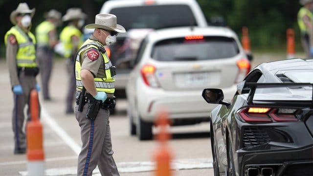 Polizisten kontrollieren kontrollieren Autofahrer bei der Einreise von Louisiana nach Texas, um zu überprüfen, ob diese sich in eine 14-tägige Selbstquarantäne begeben müssen. Polizisten kontrollieren kontrollieren Autofahrer bei der Einreise von Louisiana nach Texas, um zu überprüfen, ob diese sich in eine 14-tägige Selbstquarantäne begeben müssen.