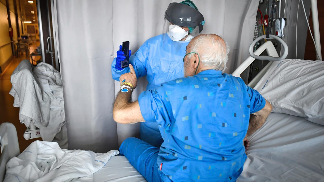 Ein Mitarbeiter des Krankenhauses Johannes Paul XXIII. in Bergamo hilft einem älteren Covid-19-Patienten dabei, mit seiner Familie per Videoanruf Kontakt zu halten.