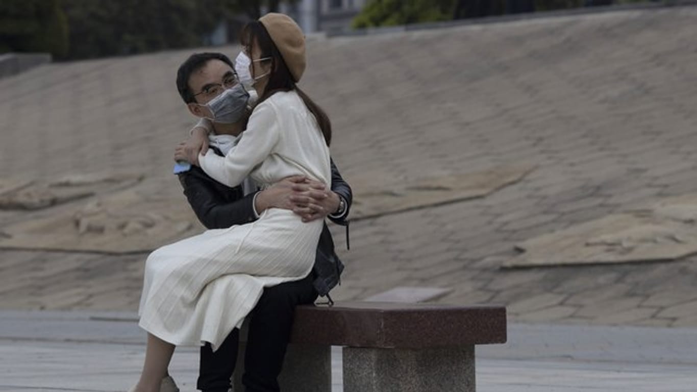 Ein Paar mit Mundschutz sitzt auf einer Bank im chinesischen Wuhan.