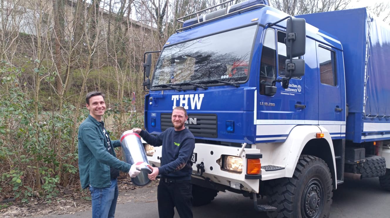 Constantin Sonnen vom Makerspace Hammertime und ein Mitarbeiter des THW tauschen eine Lieferung aus.