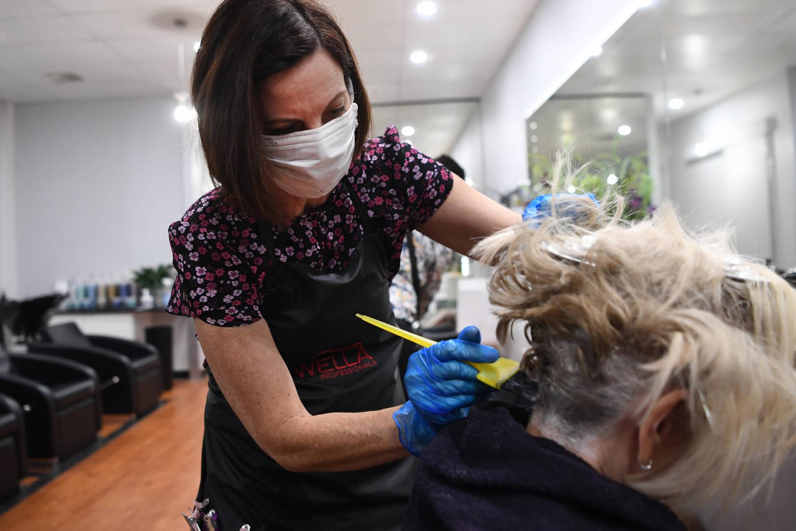 Eine Friseurin mit Mundschutz: In den europäischen Nachbarländern werden die Corona-Maßnahmen nach und nach gelockert.