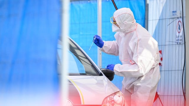 Ein Mitarbeiter führt in einem Corona-Abstrichzentrum einen Test durch. Ein Mitarbeiter führt in einem Corona-Abstrichzentrum einen Test durch.