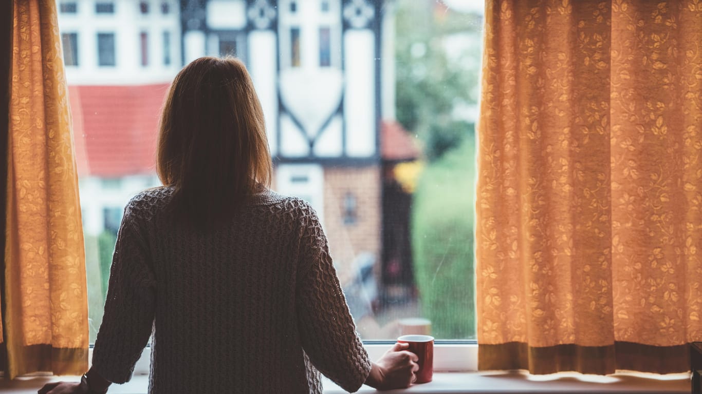 Eine Frau am Fenster: Wer sich einsam fühlt, sollte versuchen, mit Menschen in Kontakt zu treten.