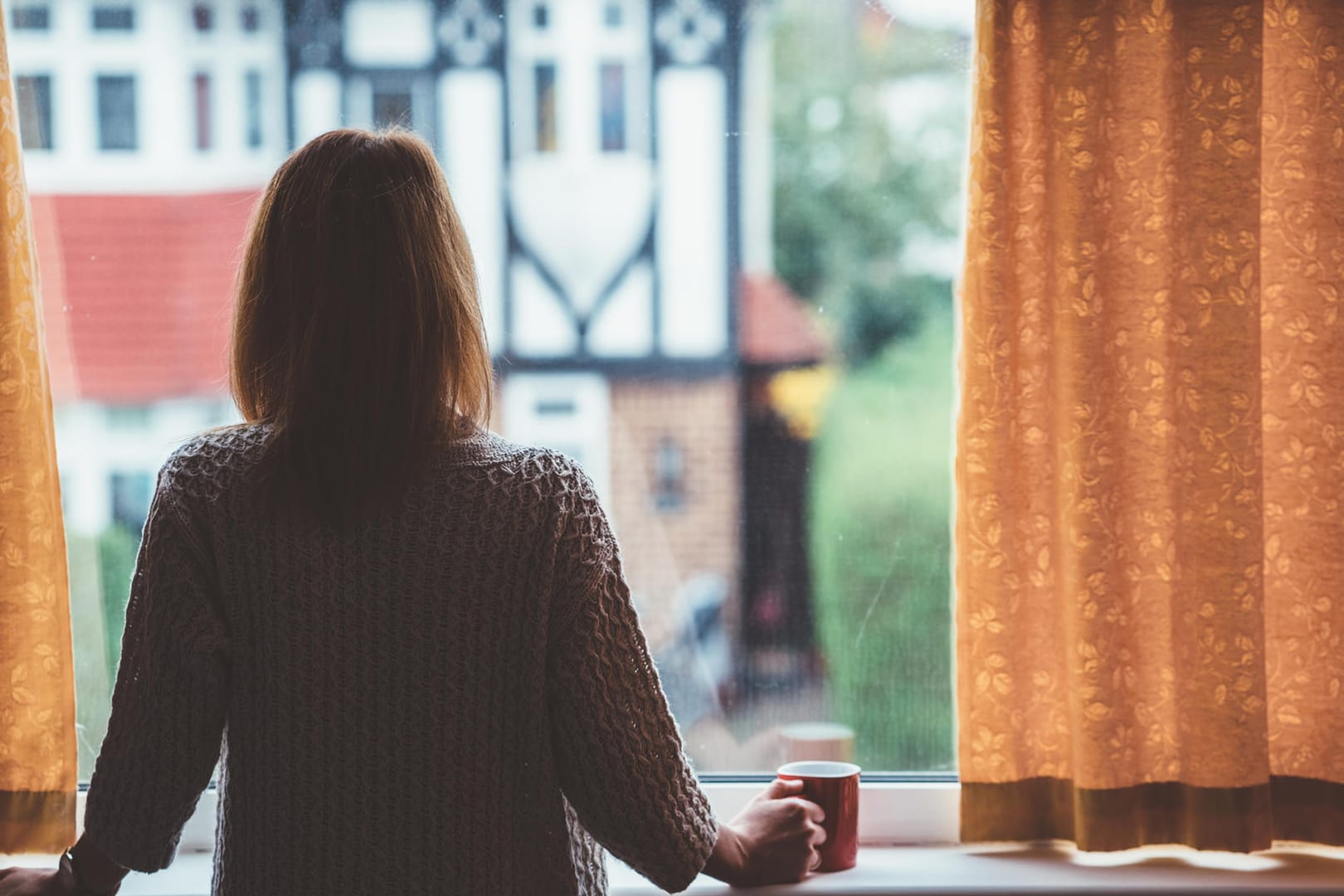 Eine Frau am Fenster: Wer sich einsam fühlt, sollte versuchen, mit Menschen in Kontakt zu treten.