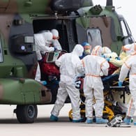 Ein schwer an Covid-19 erkrankter Patient aus Frankreich wird auf dem Flughafen Dresden aus einem Nato-Helikopter getragen.