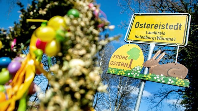 Ein Schild mit der Aufschrift "Frohe Ostern" hängt unter dem Ortsschild am Ortseingang von Ostereistedt.