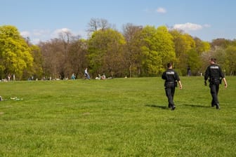 Zwei Polizisten gehen durch den Englischen Garten in München.