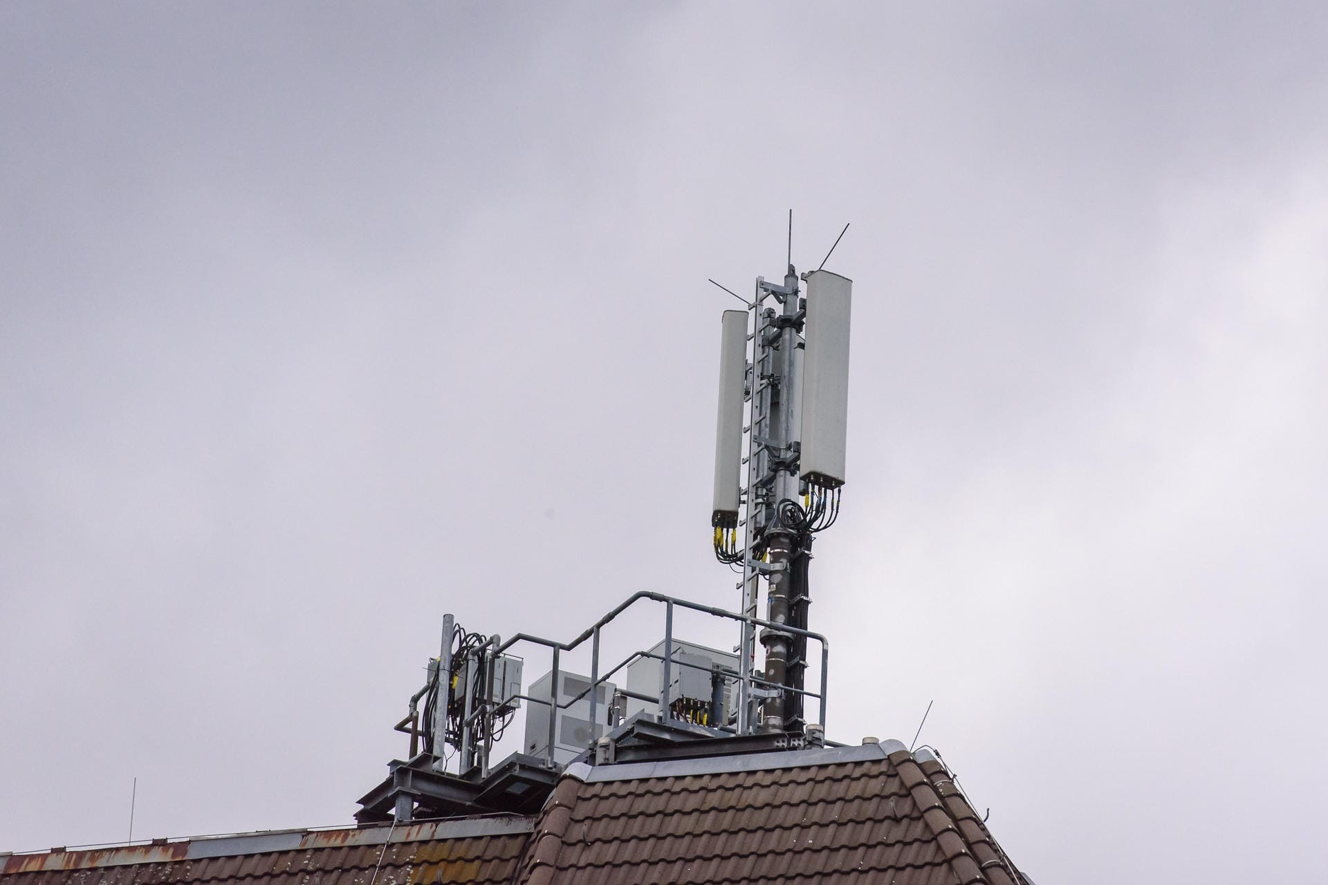 Ein Handy-Sendemast auf einem Hausdach (Symbolbild): 1&1 kann sein eigenes Handynetz nicht im September in Betrieb nehmen.