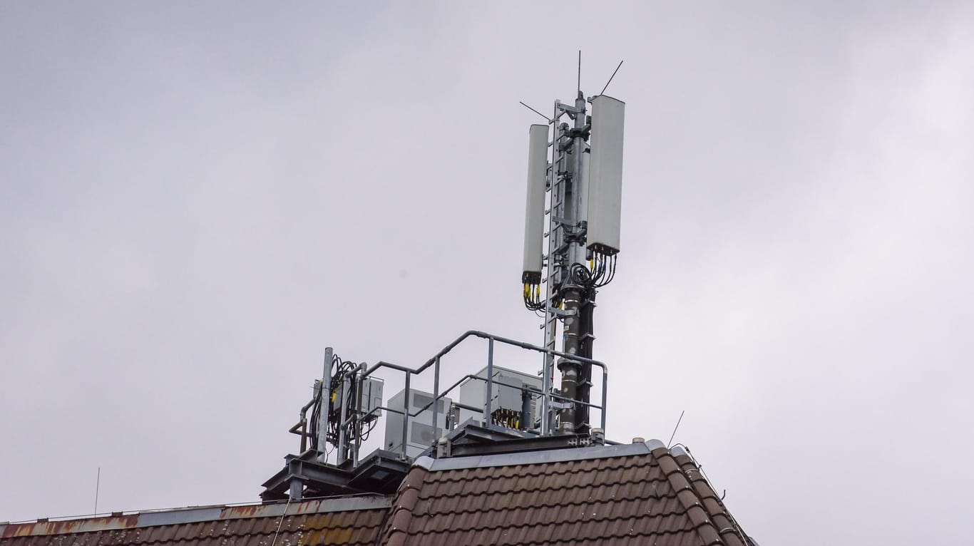 Ein Handy-Sendemast auf einem Hausdach (Symbolbild): 1&1 kann sein eigenes Handynetz nicht im September in Betrieb nehmen.