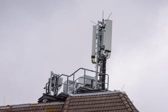 Ein Handy-Sendemast auf einem Hausdach (Symbolbild): 1&1 kann sein eigenes Handynetz nicht im September in Betrieb nehmen.