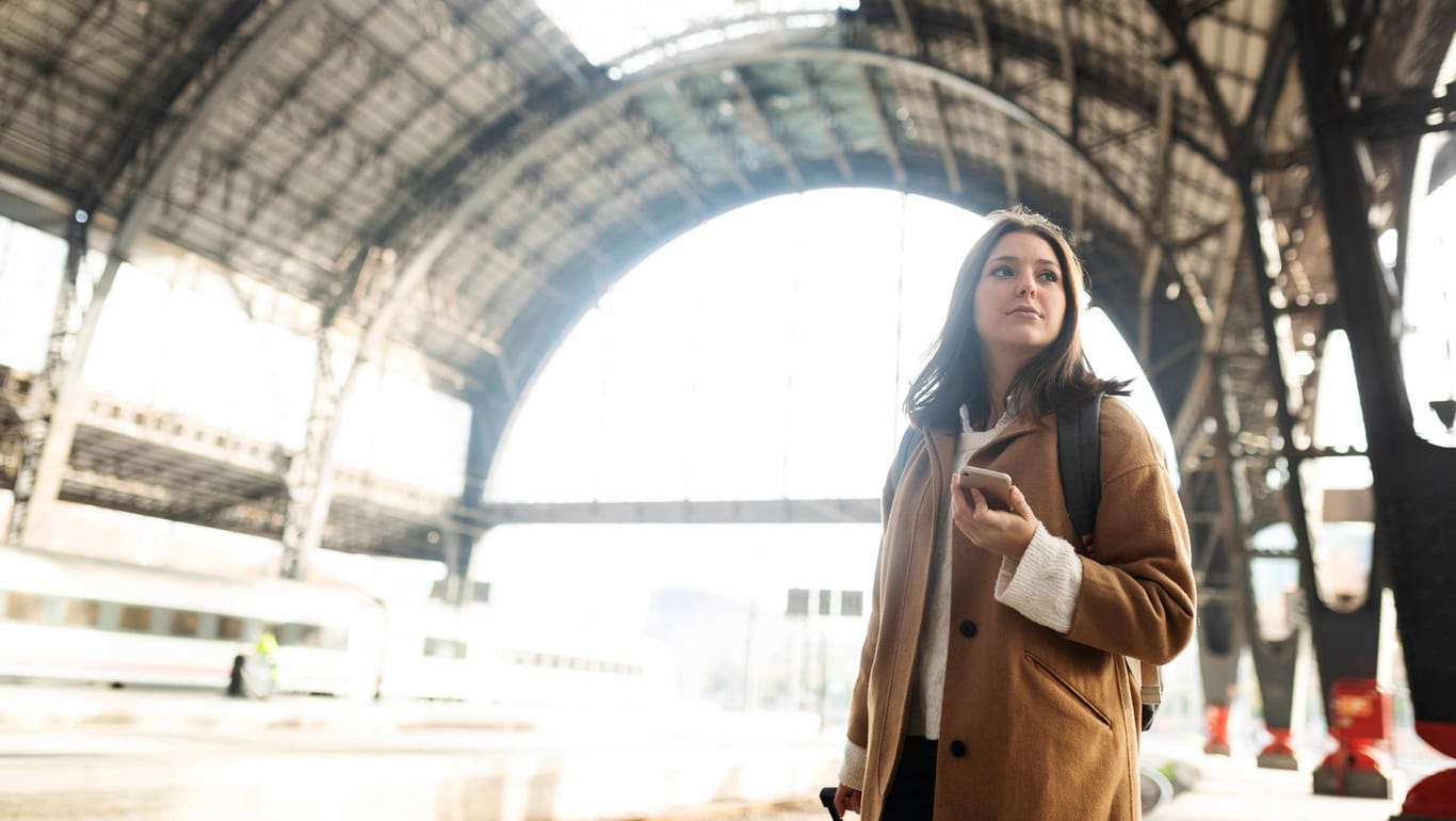 Eine Frau mit Smartphone wartet auf ihren Zug: Die Netzbetreiber sollen auch entlang der Schienenwege für eine gute Mobilfunkabdeckung sorgen.