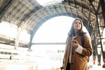 Eine Frau mit Smartphone wartet auf ihren Zug: Die Netzbetreiber sollen auch entlang der Schienenwege für eine gute Mobilfunkabdeckung sorgen.