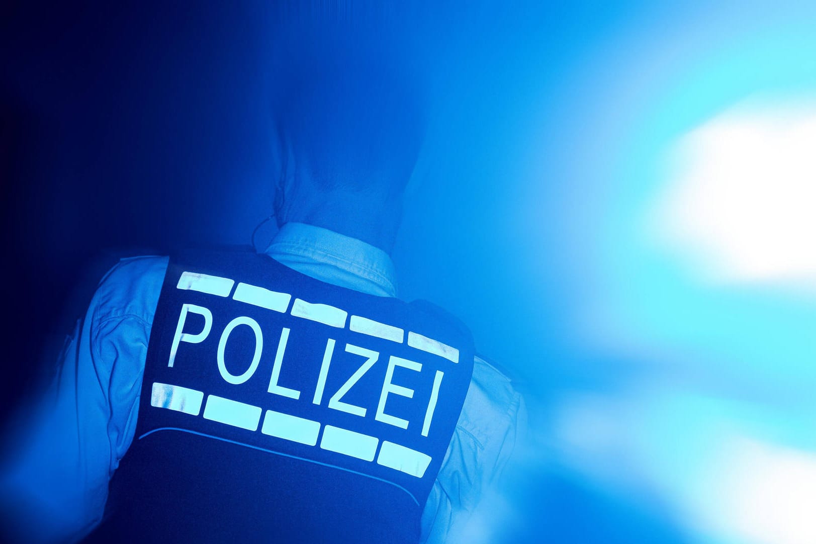 Ein Polizist wird con Blaulicht angestrahlt: In Hagen ist ein 27-Jähriger von einen Unbekannten geschlagen worden (Symbolbild).