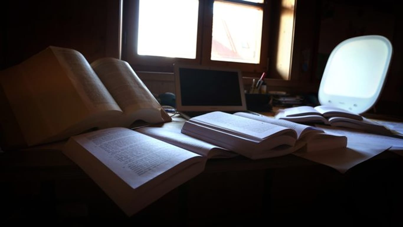 Lehrbücher und Unterlagen liegen auf dem Schreibtisch eines Studenten.