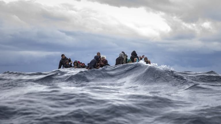 Männer aus Marokko und Bangladesch in einem überfüllten Holzboot vor der Küste von Libyen.