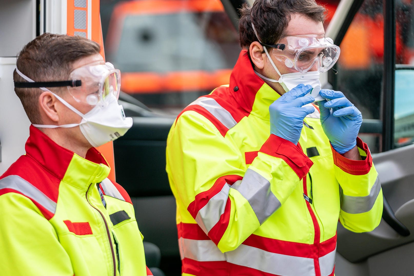 Mitarbeiter der Kölner Feuerwehr zeigen ihre Schutzausrüstung (Archivbild): Auch Notfallsanitäter, Rettungssanitäter und Rettungsassistenten haben mit den Auswirkungen des Coronavirus zu kämpfen.