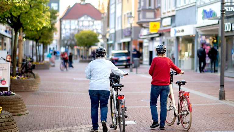 Zwei Frauen gehen mit ihren Fahrrädern durch die fast menschenleere Innenstadt von Peine (Niedersachsen). Von Montag an dürfen Geschäfte auf einer Verkaufsfläche von bis zu 800 Quadratmetern wieder öffnen.