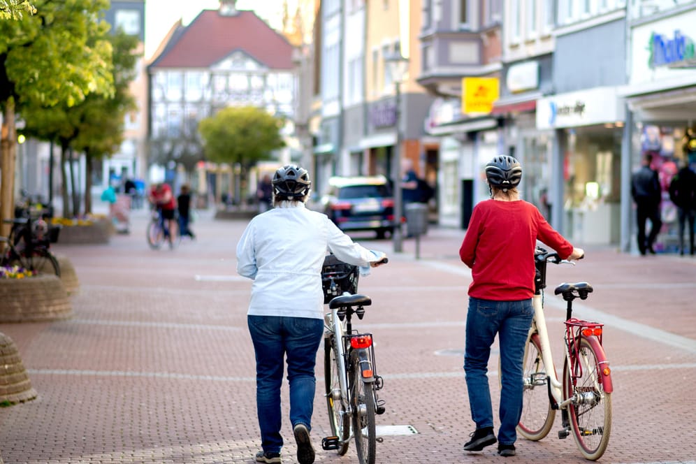 Zwei Frauen gehen mit ihren Fahrrädern durch die fast menschenleere Innenstadt von Peine (Niedersachsen). Von Montag an dürfen Geschäfte auf einer Verkaufsfläche von bis zu 800 Quadratmetern wieder öffnen.