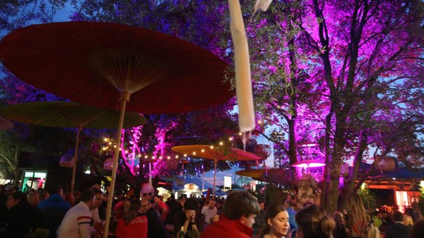 Menschen stehen bei dem Tollwood Festival in München an einer beleuchteten Bar (Archivbild): Die meisten Angebote werden nichts kosten.