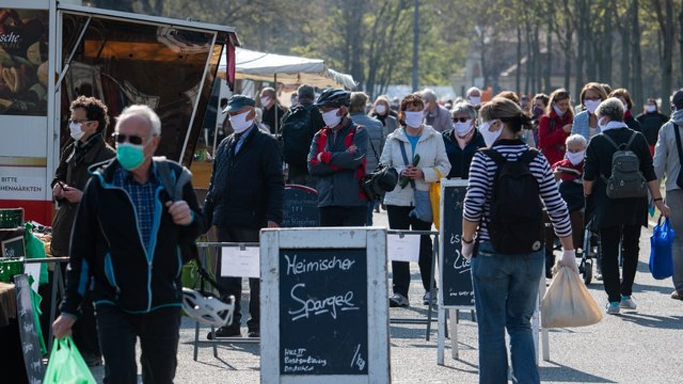 Besucher tragen auf dem Wochenmarkt in der Innenstadt von Dresden Schutzmasken.