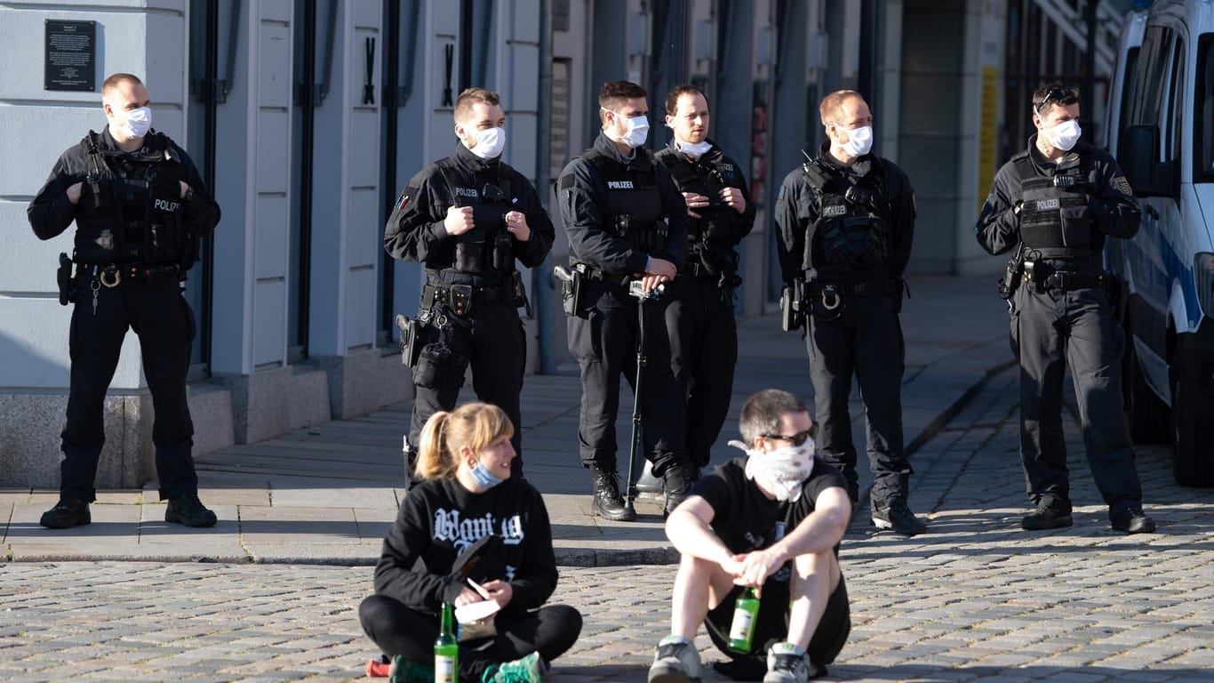 Sachsen, Dresden: Polizisten und Gegendemonstranten einer Kundgebung der islam- und ausländerfeindlichen Pegida-Bewegung stehen und sitzen mit einem Mundschutz auf dem Neumarkt.