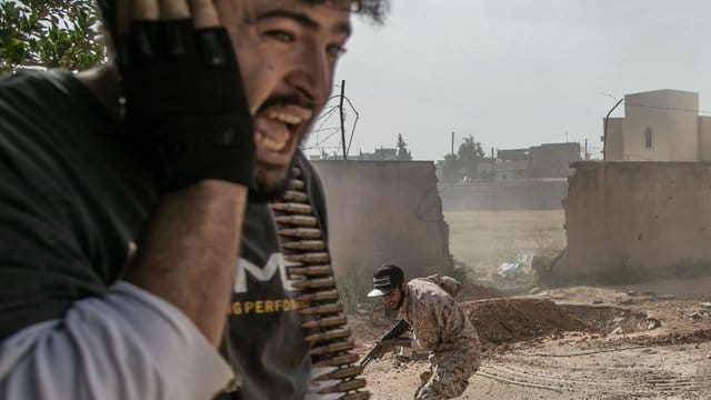 Kämpfer der Regierung gehen bei Zusammenstößen mit den Truppen der Libysch-Nationalen Armee in Deckung. Kämpfer der Regierung gehen bei Zusammenstößen mit den Truppen der Libysch-Nationalen Armee in Deckung.