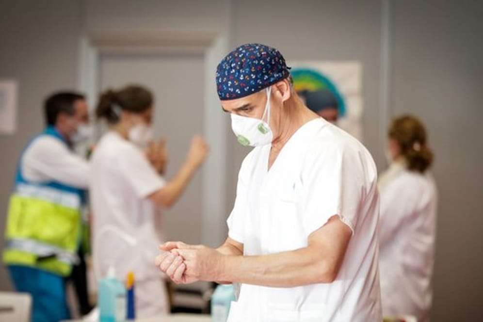 Ein Mitarbeiter des spanischen Gesundheitswesens desinfiziert seine Hände.