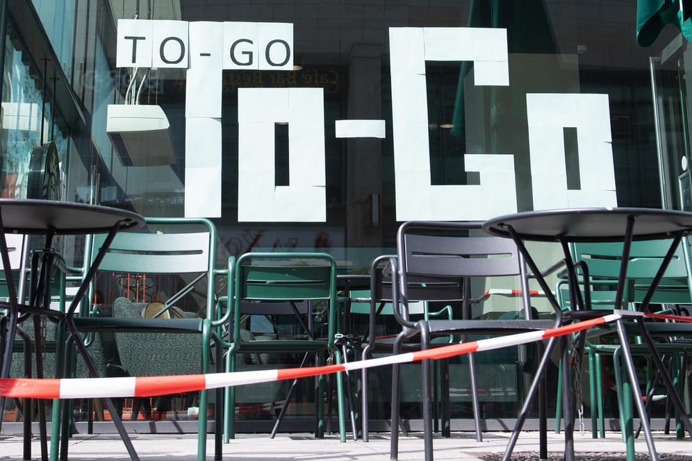 Weiße Blätter kleben in dem Fenster eines Kaffees und bilden den Schriftzug "To-Go": Außer-Haus-Lieferungen und Take-away-Angebote sind weiter erlaubt.