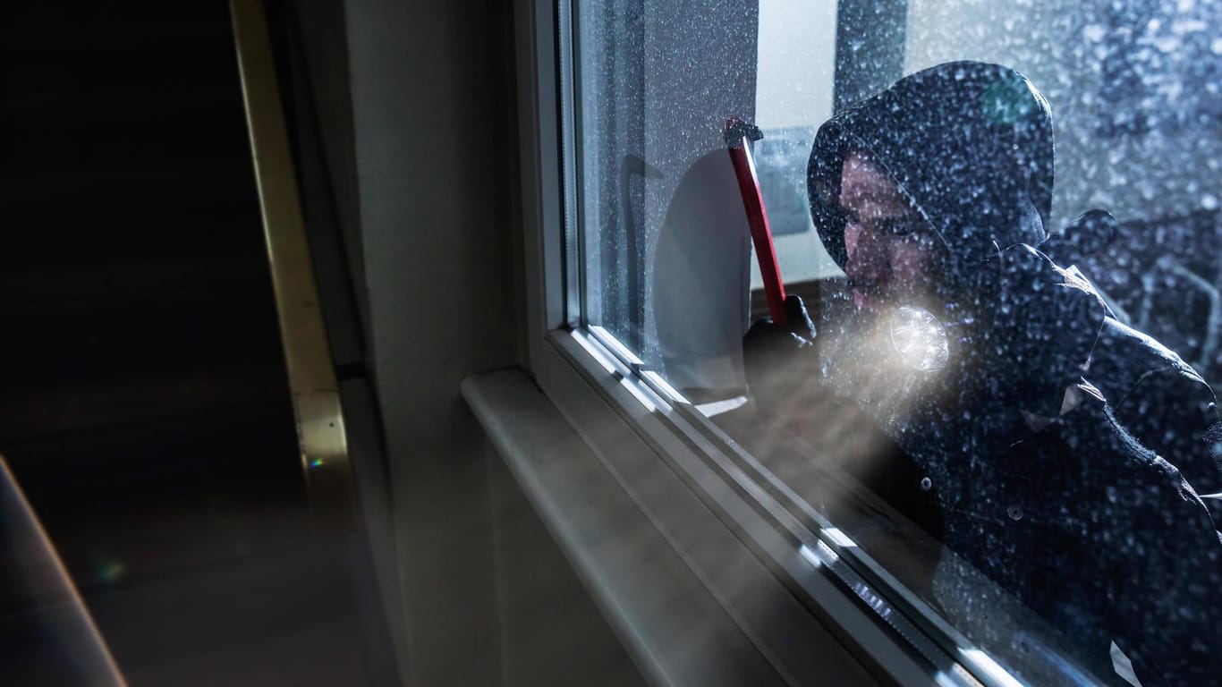 Ein Einbrecher steht vor einem Fenster (Symbolbild): In Bonn hat es in der vergangenen Nacht zwei Einbrüche gegeben.