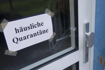 An einer Haustür hängt ein Schild mit "häuslicher Quarantäne" (Symbolbild): In Hagen haben zwei Bewohner eines Quarantäne-Hauses das Gebäude über eine Leiter verlassen.