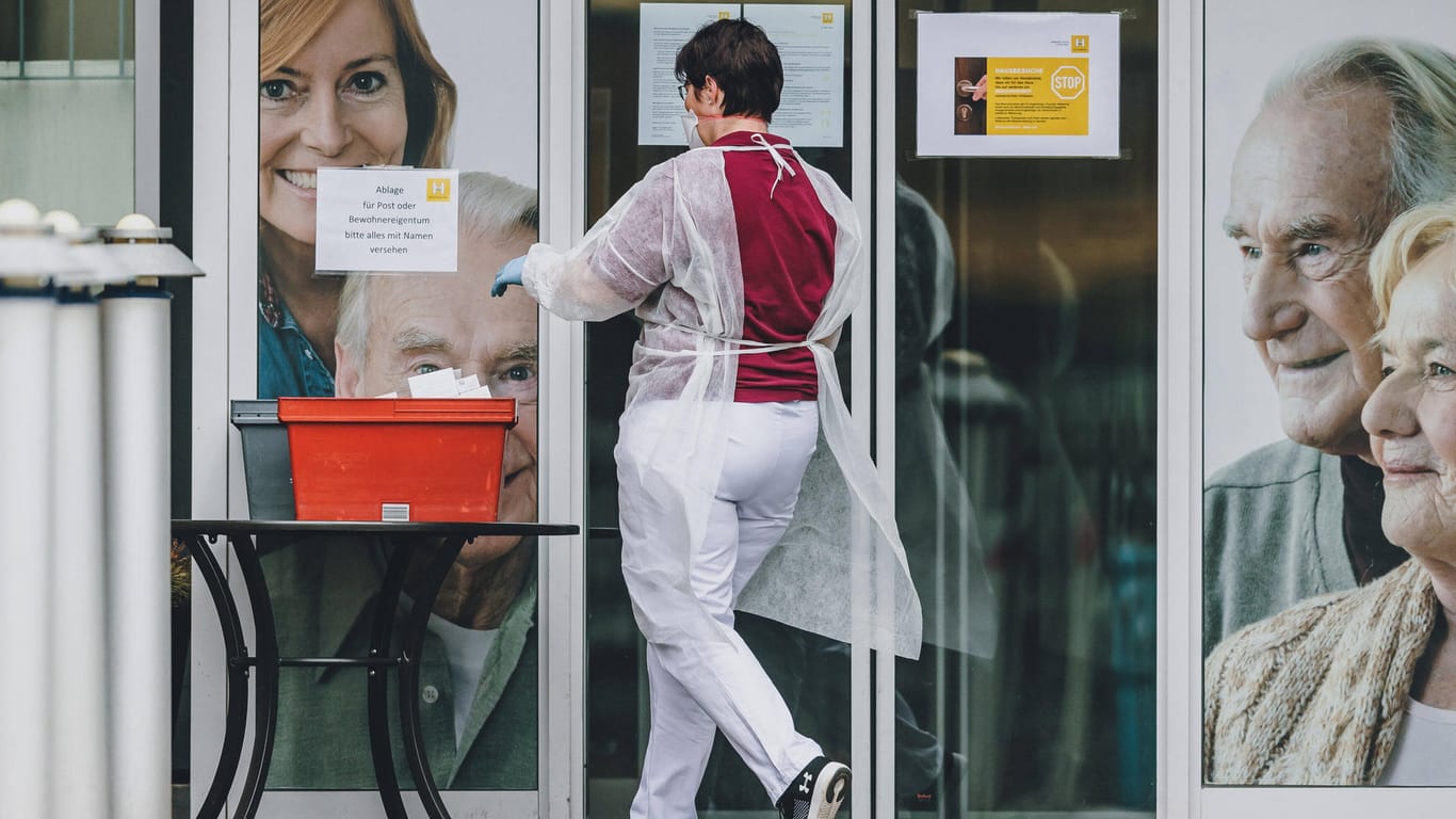 Pflege-Mitarbeiterin mit Schutzkleidung holt die abgestellte Post ab (Symbolbild): In Wolfsburg haben Pflegekräfte in den vergangenen Tagen immer wieder Anfeindungen erfahren.