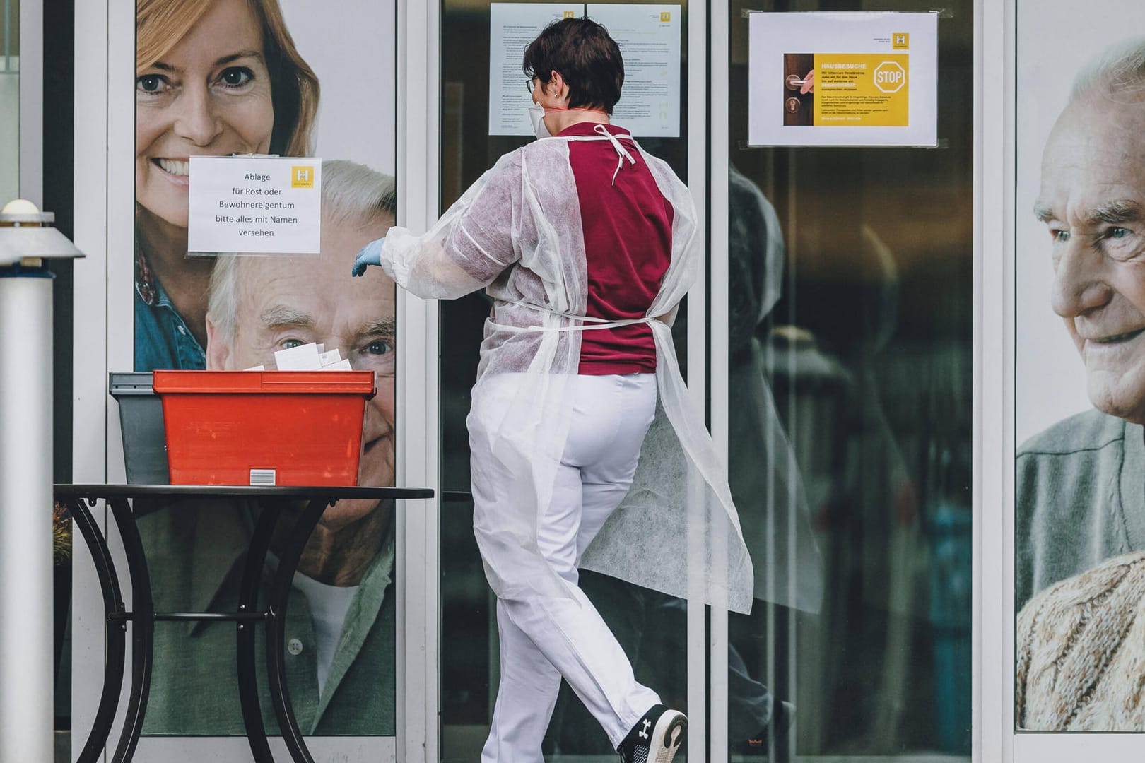 Pflege-Mitarbeiterin mit Schutzkleidung holt die abgestellte Post ab (Symbolbild): In Wolfsburg haben Pflegekräfte in den vergangenen Tagen immer wieder Anfeindungen erfahren.