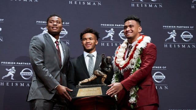 Die damaligen Heisman Trophy Finalisten: Dwayne Haskins (l-r) von Ohio State, Kyler Murray von Oklahoma, und Tua Tagovailoa von Alabama, stehen neben der Trophäe.