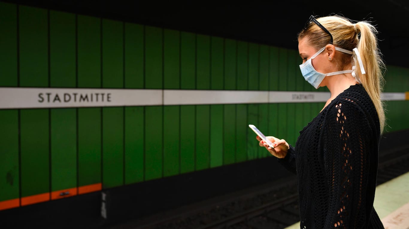 Frau mit Mundschutzmaske, am Handy, wartet auf Zug, S-Bahn, Station Stadtmitte, Corona-Krise, Stuttgart, Baden-Württembe