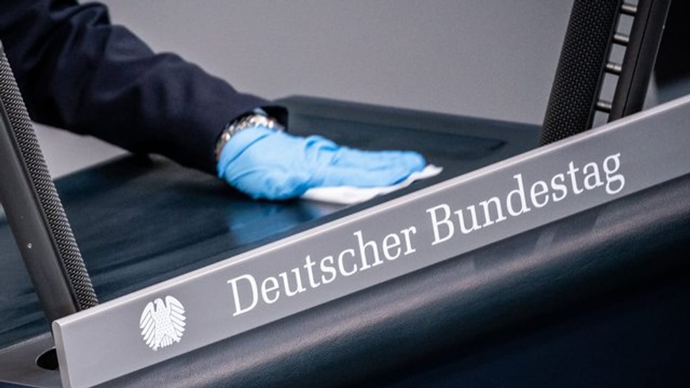 Eine Bundestagsmitarbeiterin reinigt das Rednerpult.
