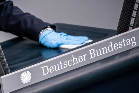Eine Bundestagsmitarbeiterin reinigt das Rednerpult.