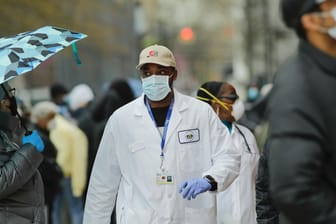 Ein Mediziner läuft durch die Wartenden vor einem Corona-Testzentrum in New York: In der Millionenmetropole könnte bereits jeder Fünfte das Virus gehabt haben.
